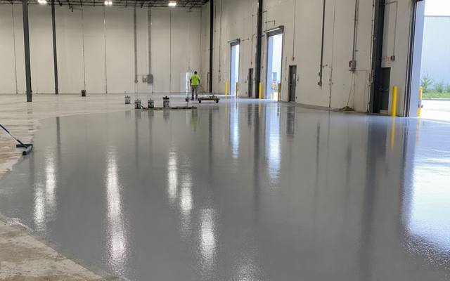Industrial floor coating being pulled out across a warehouse slab